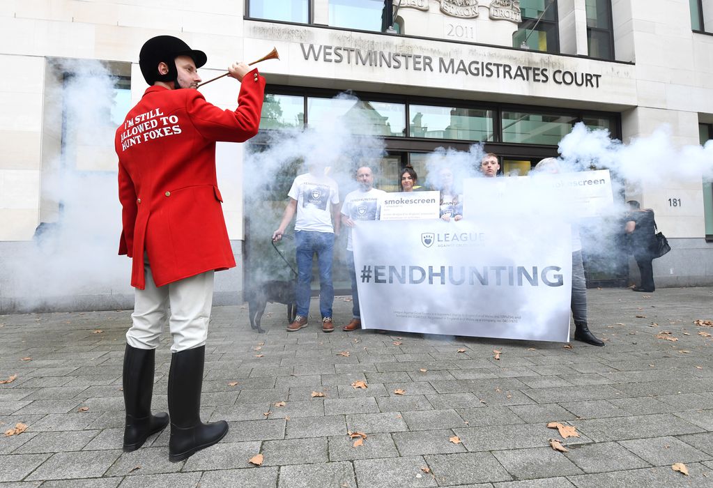 A faux "hunter" and campaigners shrouded in smoke outside court