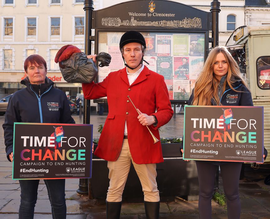 Two campaigners and a fake hunter pose in front of town board